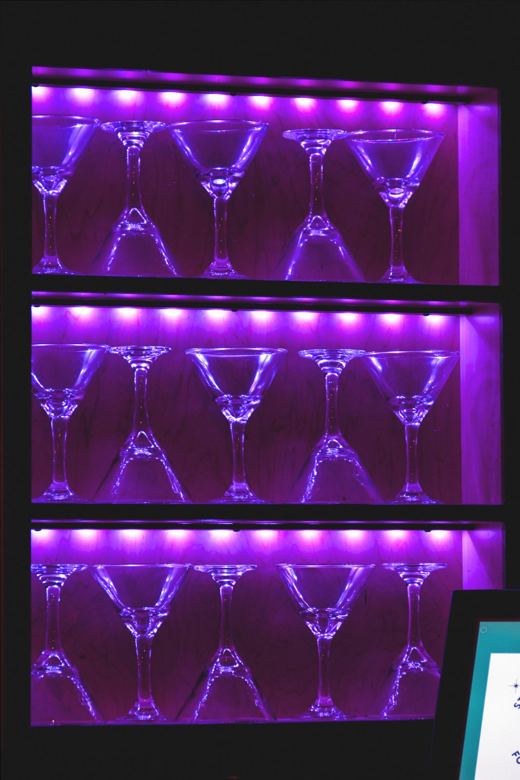 Martini glasses on purple-lit shelves