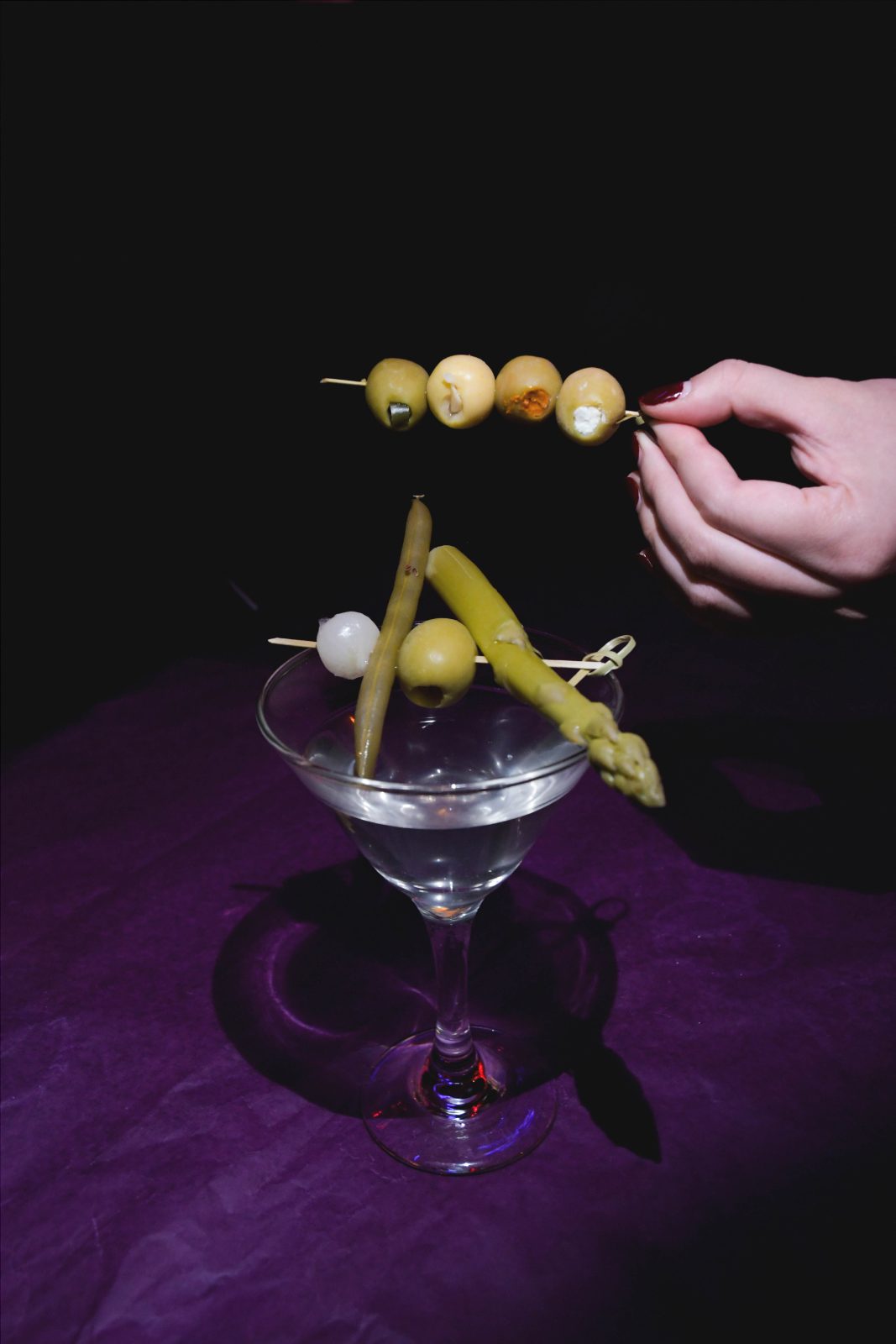 A garnish skewer lifted over a martini